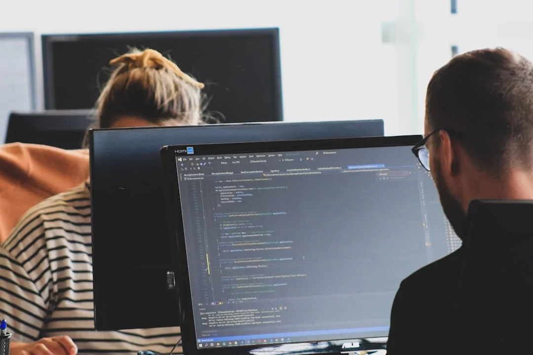 A modern workspace featuring dual computer monitors displaying web design projects, emphasizing technology and productivity.